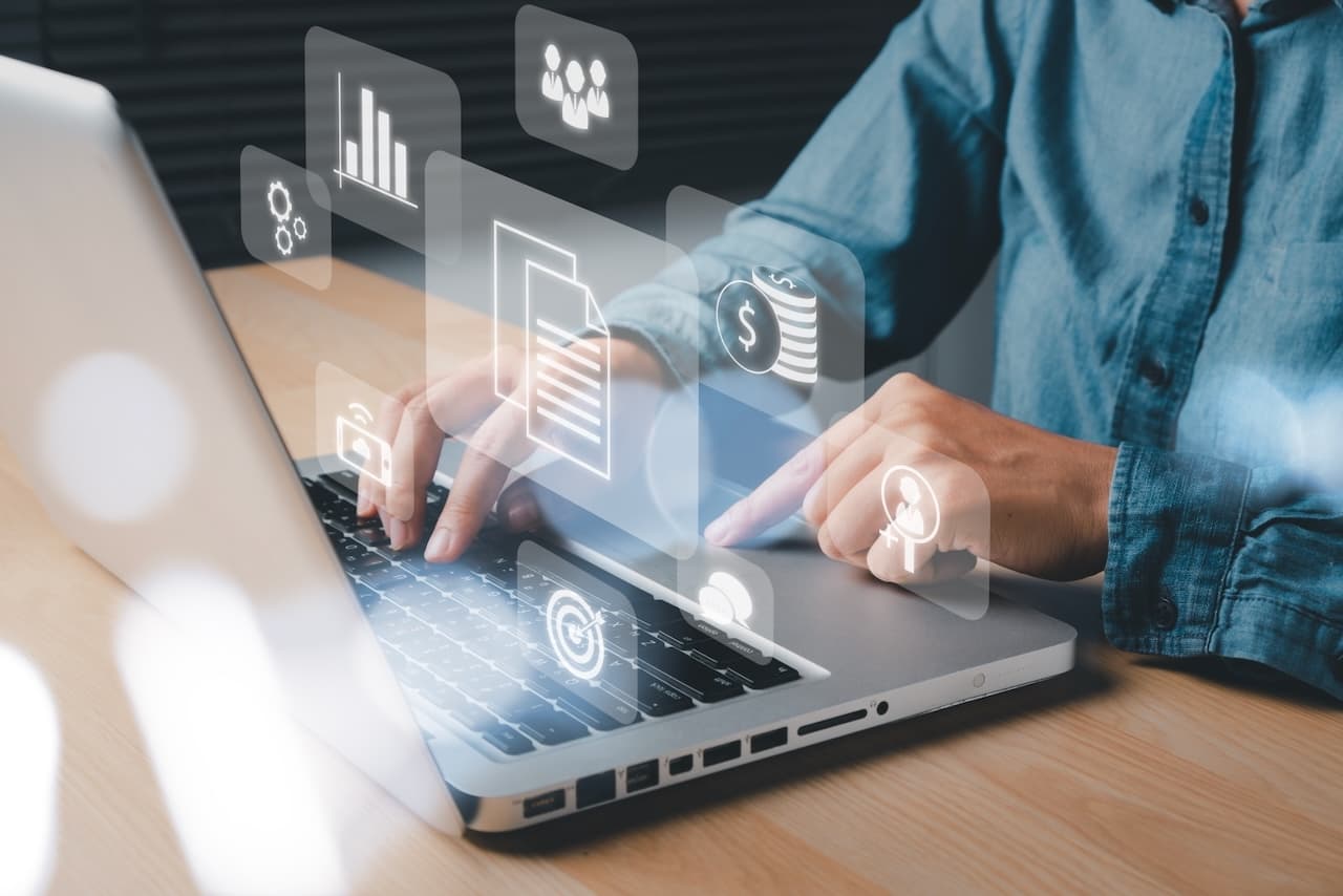 Person working on a laptop with emerging digital graphics, symbolizing the technological integration and automation in Del Bravo's logistics management