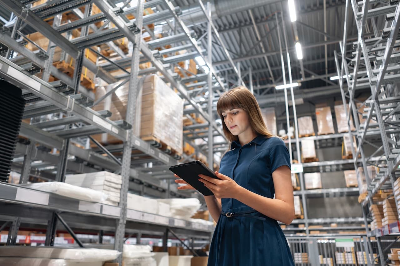 Worker checking inventory in a warehouse with a tablet, illustrating the precision and modernity in warehouse management offered by Del Bravo