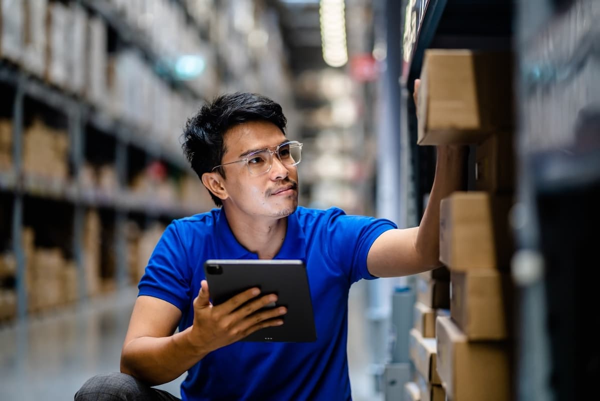 Empleado usando una tablet para gestionar inventario en un almacén, reflejando la precisión y tecnología en la logística de Del Bravo