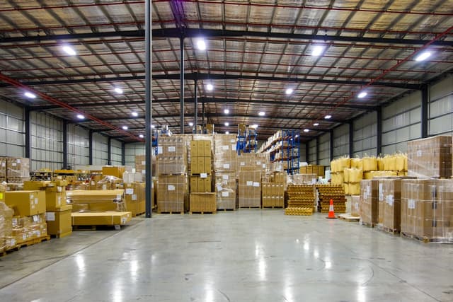 Two supervisors discussing organization strategies in a warehouse, surrounded by shelves full of products