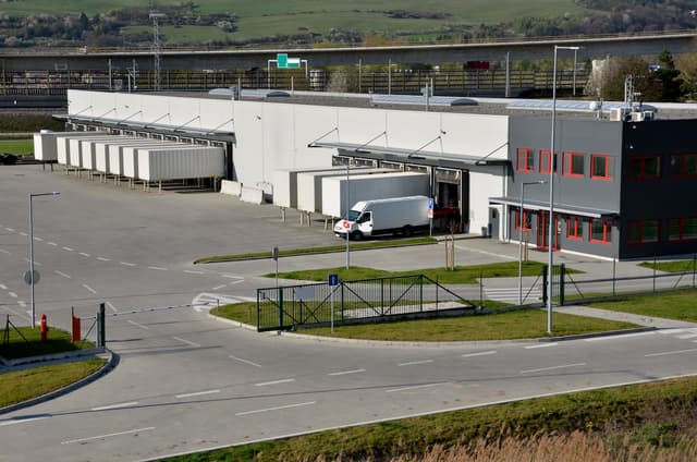 Vista de un centro de distribución con camiones estacionados, representando la infraestructura sólida y la capacidad logística de Del Bravo para manejar operaciones a gran escala