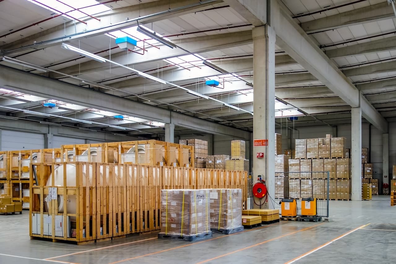 Interior de un almacén con grandes cajas de madera y palets, destacando la capacidad de Del Bravo para manejar cargas voluminosas y su eficiente organización logística