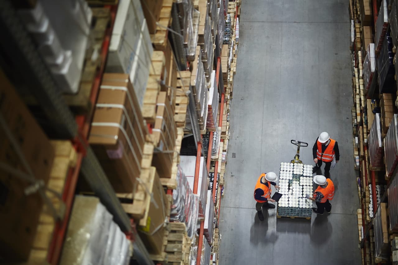 Aerial view of workers in a warehouse handling merchandise, reflecting the coordination and teamwork in inventory management by Del Bravo