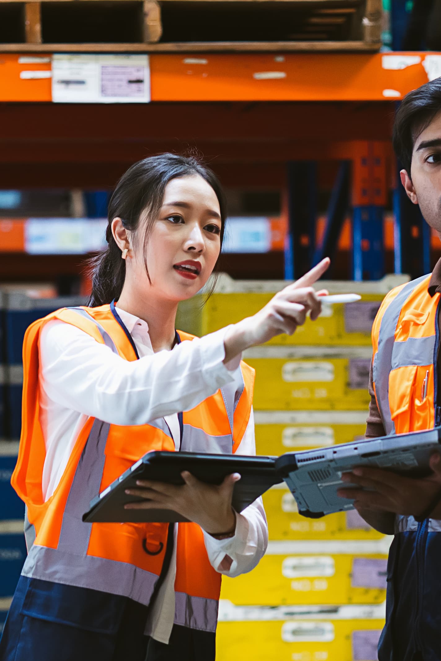 Supervisor in a warehouse using a tablet and giving instructions, highlighting the coordination and leadership in Del Bravo's logistics management