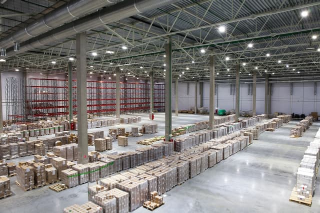 Person holding a tablet showing inventory management graphics in a warehouse