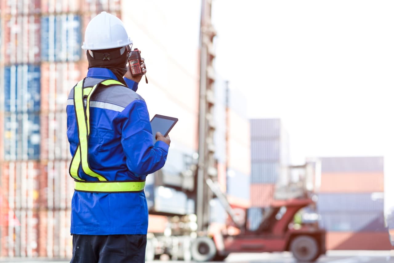 Logistics operator using advanced technology to manage containers at a port, demonstrating Del Bravo's operational efficiency