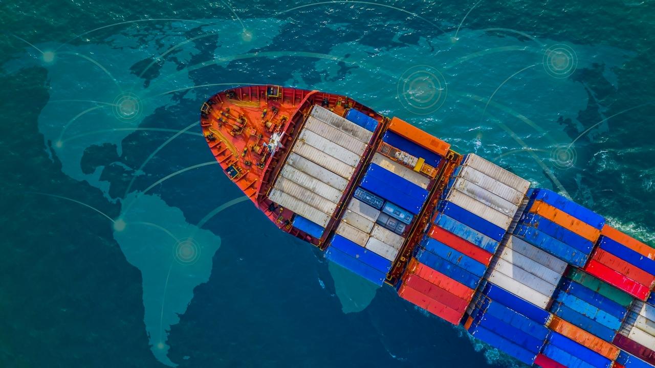 Vista aérea de un barco carguero lleno de contenedores navegando en aguas internacionales, reflejando la capacidad de Del Bravo en la gestión eficiente del transporte marítimo