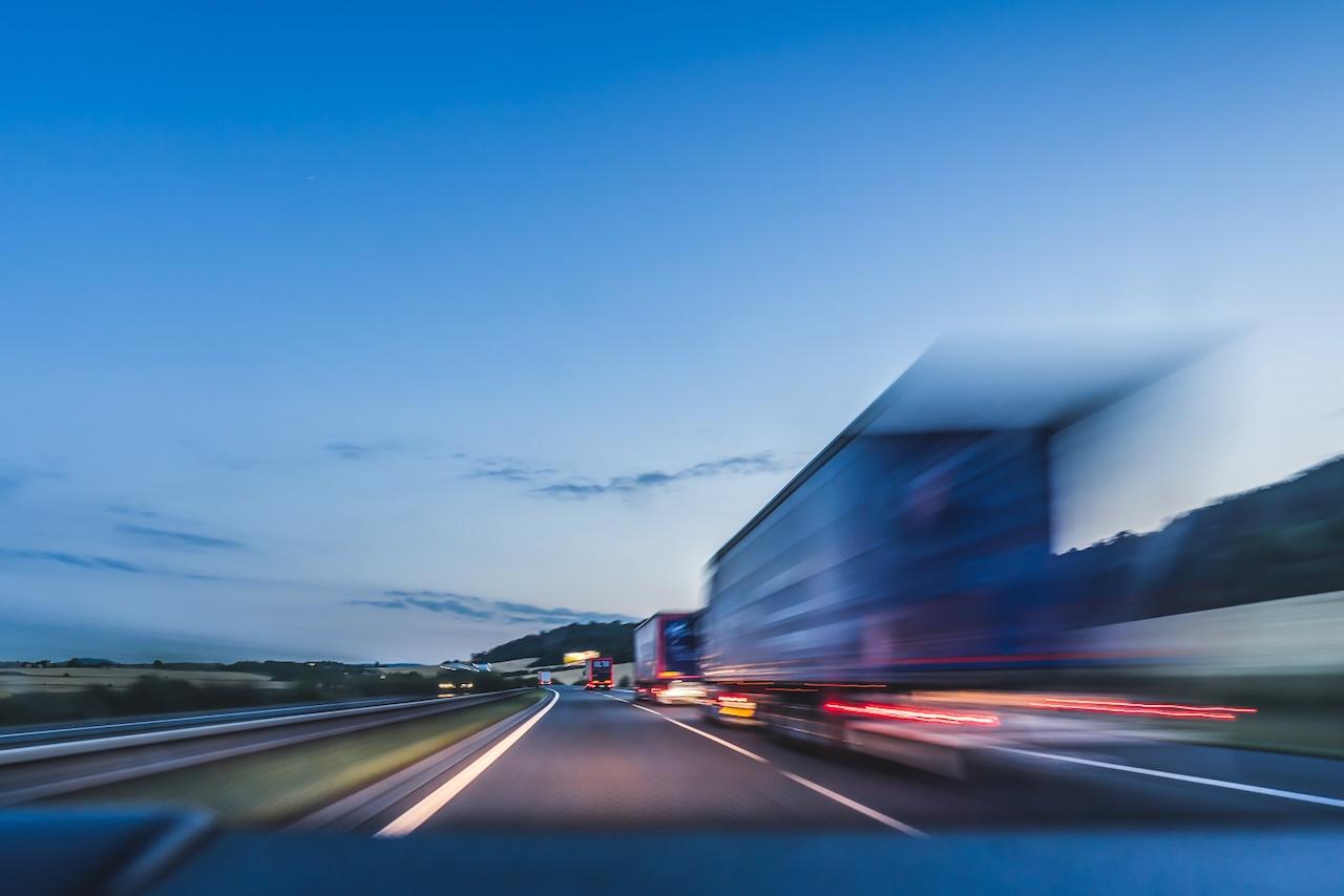 Camiones en una autopista al atardecer, simbolizando la rapidez y confiabilidad en el transporte terrestre que ofrece Del Bravo